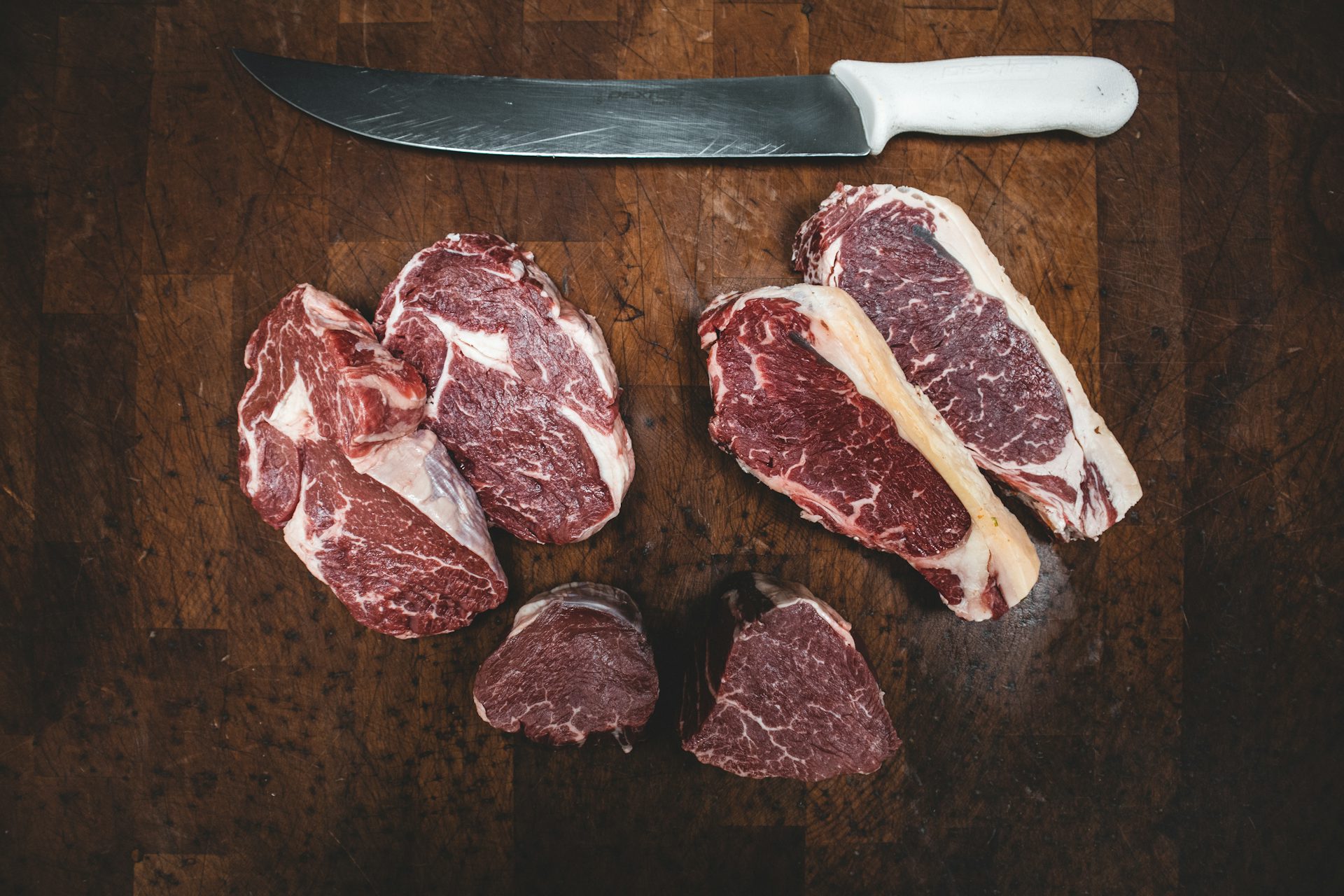 Cortes de carne bovina sendo preparados sobre tábua de madeira